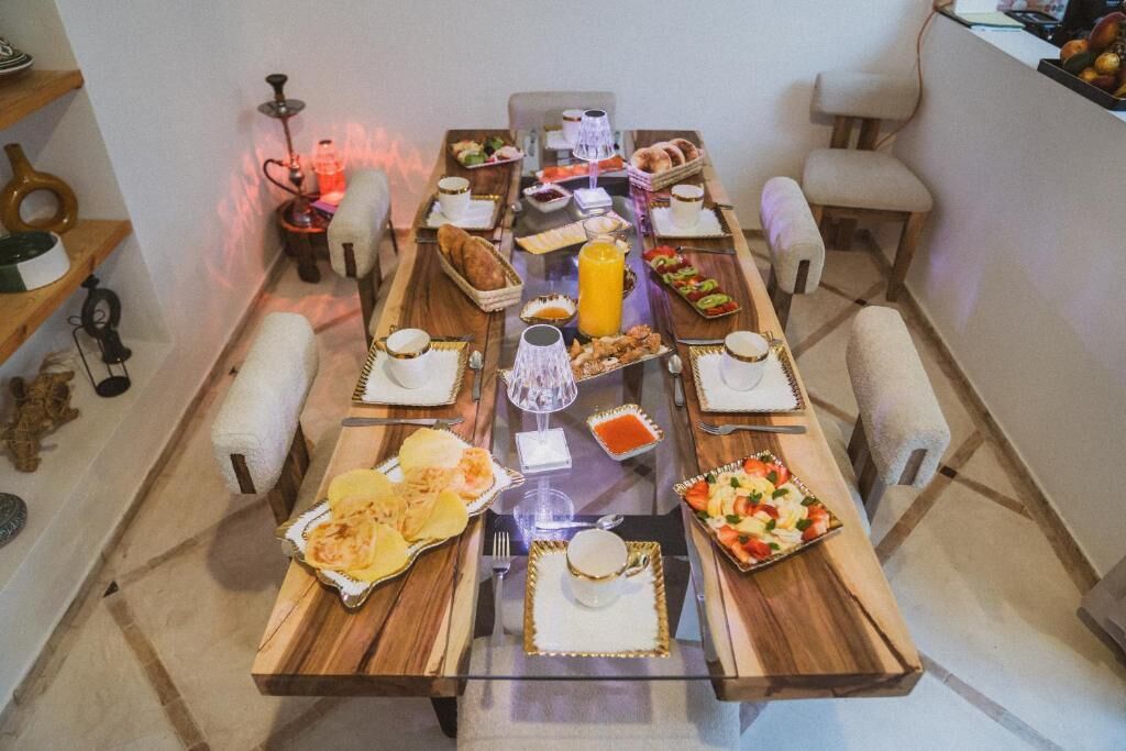 Une table à manger dressée avec différents plats, un narguilé et une bougie.