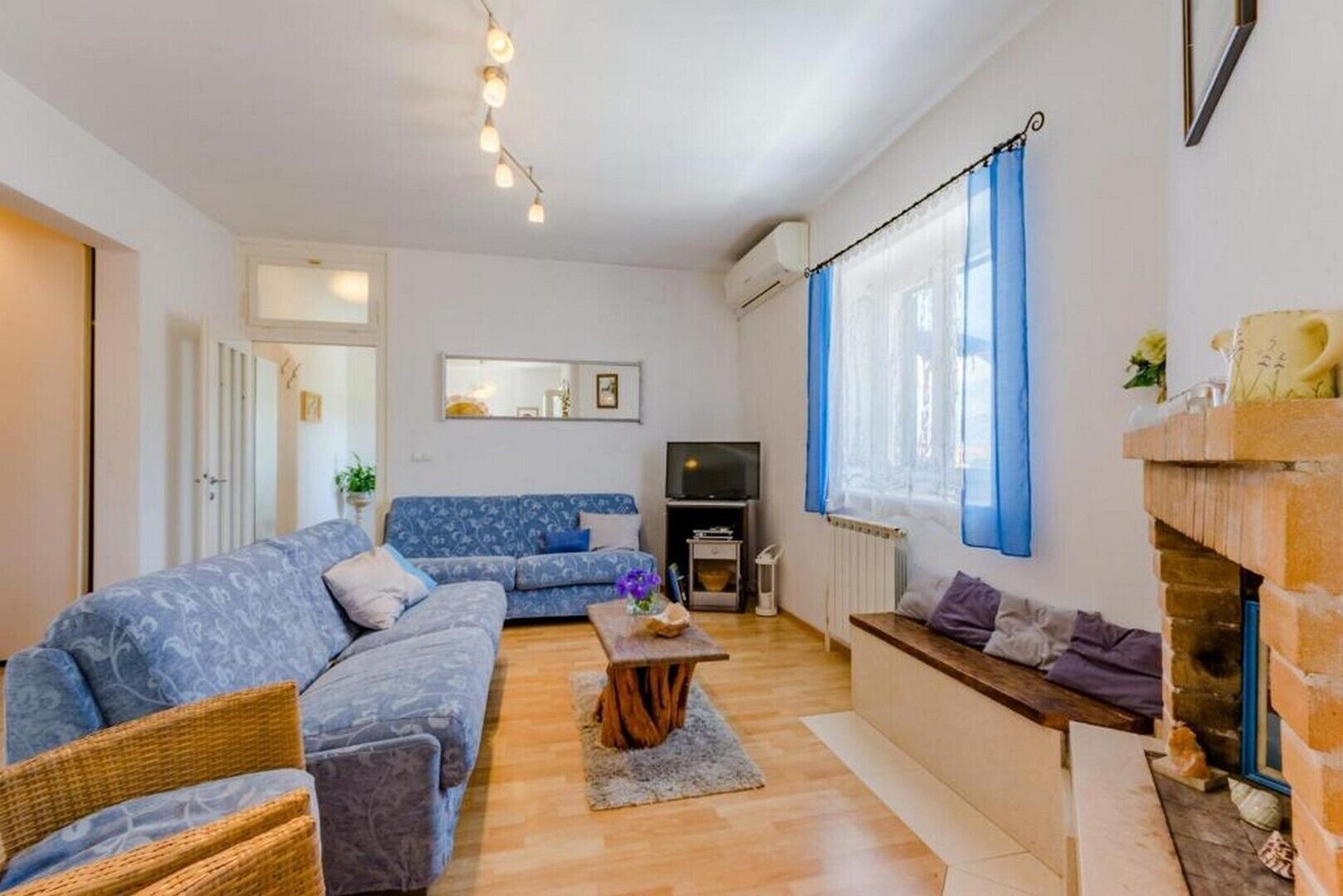 A living room with a sofa, a television, a fireplace, and a window with curtains.