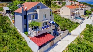 Un immeuble à plusieurs étages doté de balcons, d’une piscine et d’une terrasse surmontée d’un toit rouge.