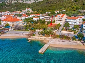 An aerial view of a coastal town with buildings, a beach, and clear blue waters. - Villa One Step to Beach with Indoor Pool (Kuciste)
