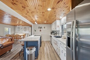 A modern kitchen with wooden ceiling, stainless steel appliances, and a central island. - Peaceful Nest: Hot Tub, Fireplace, Fire Pit & MORE (Sevierville)