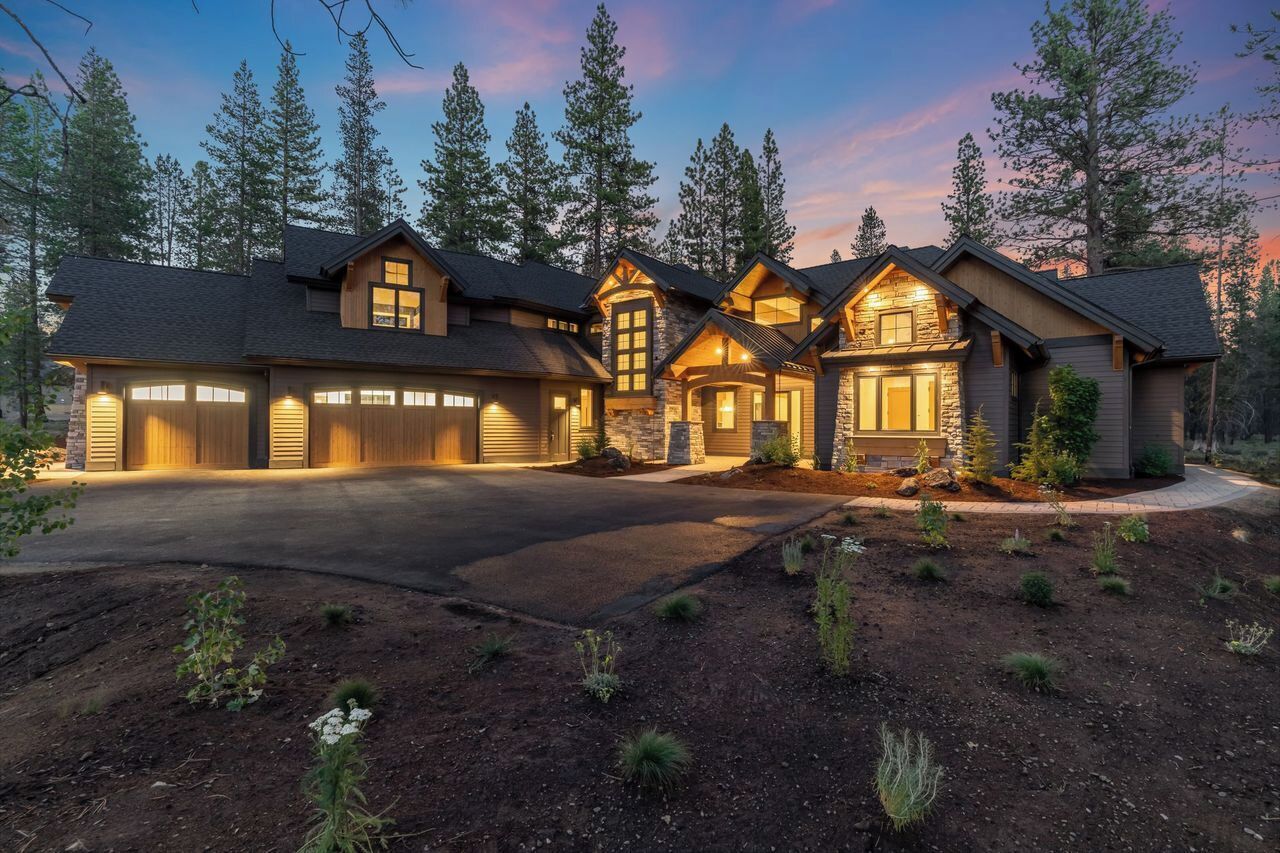 A multi-story house with a driveway, surrounded by trees.