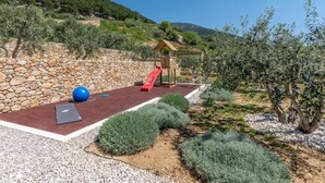 Un parque infantil con un tobogán, una pelota y una estructura de madera.