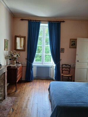 A bedroom with a wooden floor, a bed, a dresser, a chair, a radiator, and a window with curtains. - Large family home in the heart of nature near the Brière regional park (12p) (Saint-Lyphard)