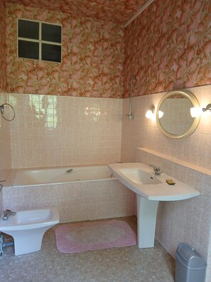 Ein Badezimmer mit Badewanne, Waschbecken, Spiegel und einem kleinen Fenster.