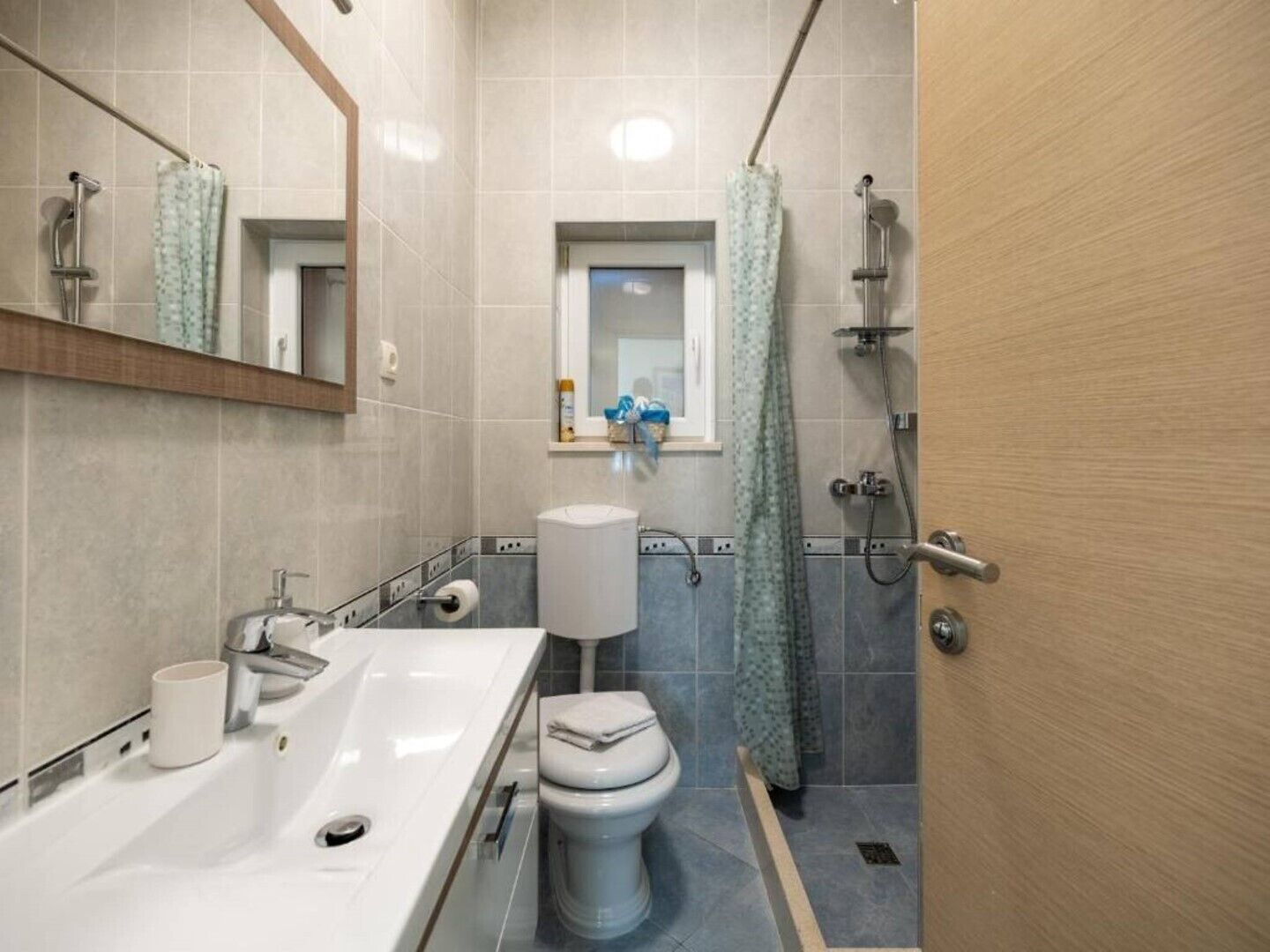 Un bagno con lavandino, water, doccia e specchio.