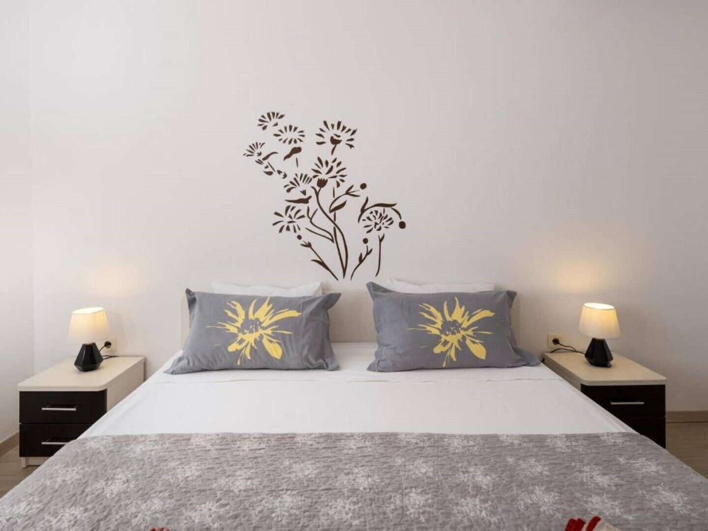 Un dormitorio con una cama, dos mesitas de noche y una decoración en la pared.