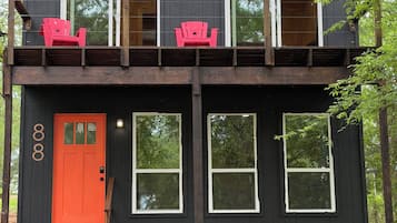 Une cabane à deux étages avec un balcon, une porte rouge et le numéro « 808 » peint sur le côté.