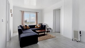 Een moderne woonkamer met een hoekbank, een salontafel en uitzicht op het groen.