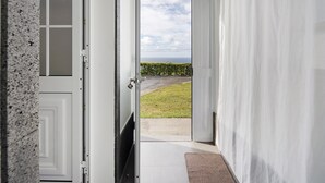 Een gang die uitkomt op een balkon met uitzicht op een grasveld en een verre horizon.
