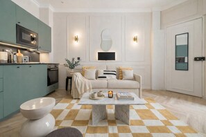 A modern living room with a checkered floor, a sofa, a coffee table, and a kitchen area with a microwave and cabinets. - Nice apartment 1BDR/4PAX in Opera (Paris)