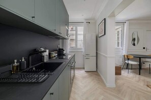 Een moderne keuken met een zwart aanrecht, grijze kastjes en een koelkast met dubbele deuren.