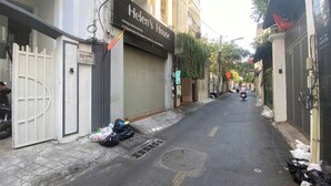 Una stretta via con negozi chiusi, un ingresso chiuso da cancello e una motocicletta parcheggiata.
