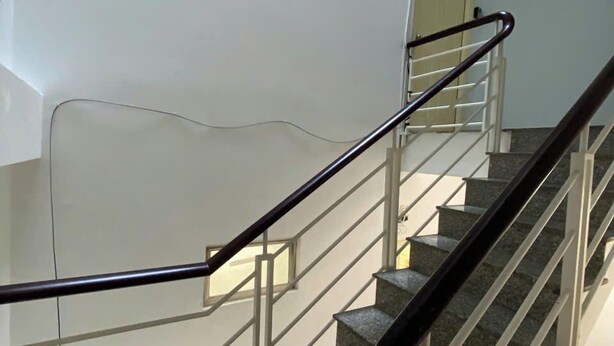 Una scala con ringhiere in metallo, una porta in cima e una piccola finestra nel muro.