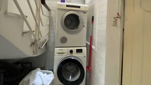 Una sala de lavandería con dos lavadoras apiladas, un tendedero y una cesta.