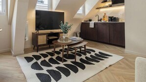 Una habitación estilo loft con televisión, comedor y cocina.