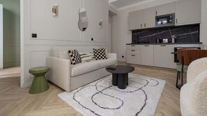 Una sala de estar moderna con un sofá, una mesa de centro y una zona de cocina con armarios y un microondas.