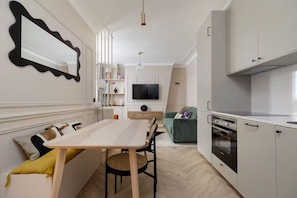 Eine moderne Küche mit Essbereich, einem an der Wand montierten Fernseher und einem eingebauten Backofen.