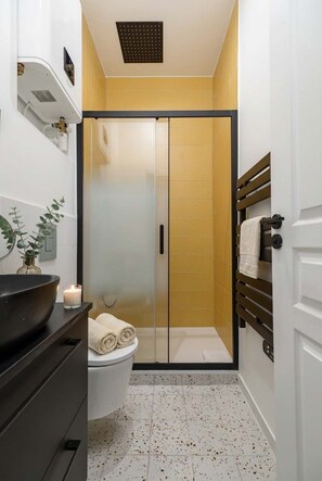 Ein Badezimmer mit Toilette, Waschbecken, Duschkabine und Handtuchhalter.