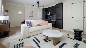 Ein modernes Wohnzimmer mit einem weißen Sofa, einem runden Couchtisch und einem schwarz-weißen Teppich.