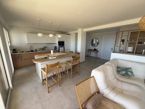 A modern kitchen with a central island, dining area with chairs, a sofa, and a mirror. - VAL D'AZUR Panoramic Sea View - Air-conditioned 4-room apartment - Center and Beach (Bandol)
