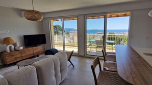 A living room with a sofa, TV, and dining area with chairs and a table. - VAL D'AZUR Panoramic Sea View - Air-conditioned 4-room apartment - Center and Beach (Bandol)