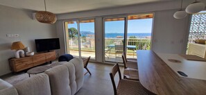 A living room with a sofa, TV, and dining area with chairs and a table. - VAL D'AZUR Panoramic Sea View - Air-conditioned 4-room apartment - Center and Beach (Bandol)