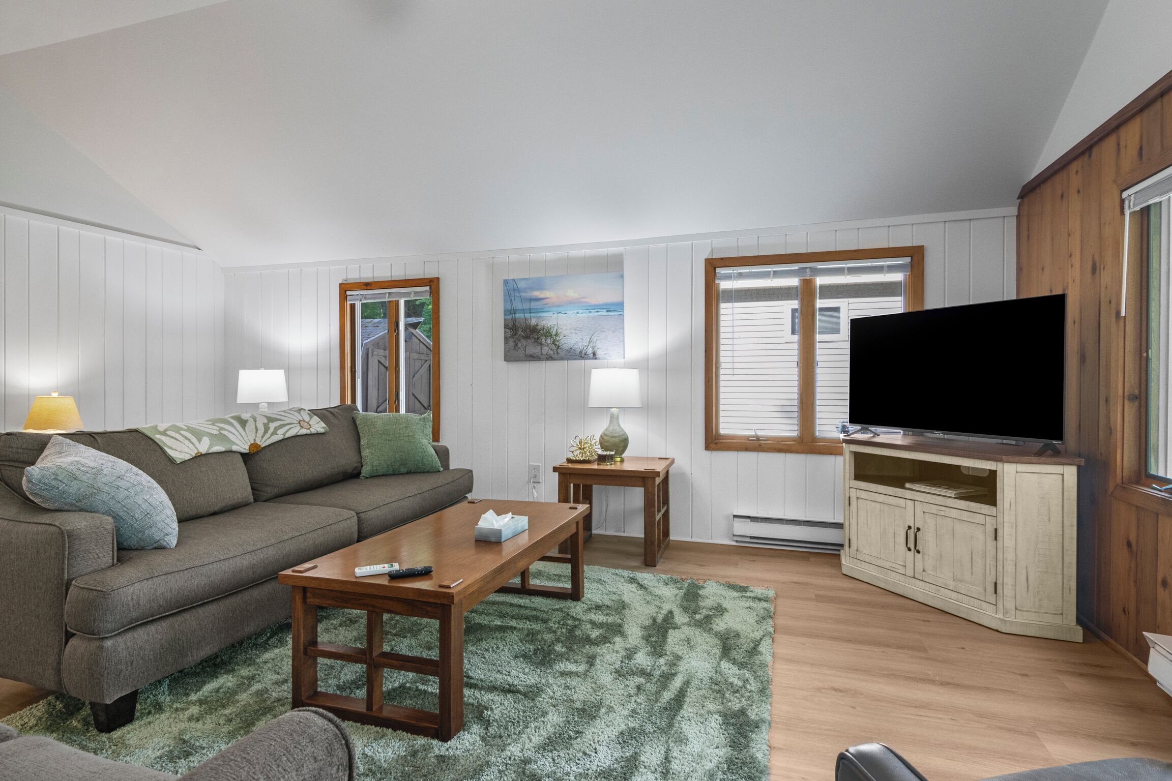 A living room with a sofa, coffee table, TV, and a painting on the wall.