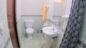 A bathroom with a toilet, sink, and shower curtain. - Machu Picchu Land (Aguas Calientes)