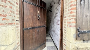 A hallway with a wooden door, brick walls, and a tiled floor.