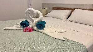 Ein Bett mit einer grün gemusterten Bettdecke, weißen Kissen und einer dekorativen Handtuchgestaltung darauf.
