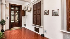 Un corridoio con pavimento piastrellato, una porta in legno e un condizionatore d'aria a parete.