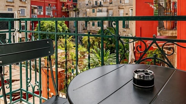 Un balcone con un tavolo rotondo e sedie, con vista su una fila di edifici colorati.
