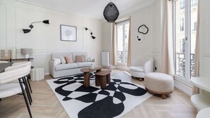 Una sala de estar moderna con un sofá, sillas, una mesa de centro y un tapete geométrico.