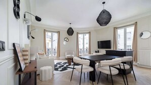 Una sala de estar moderna con comedor, ventanas grandes y un televisor de pantalla plana.