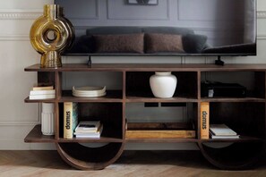 Ein Holz-TV-Schrank mit Regalen, einer weißen Vase und Büchern.