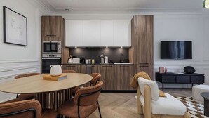 Una cucina moderna con elettrodomestici integrati, un'area pranzo con un tavolo rotondo e sedie, e un televisore a schermo piatto montato a parete.
