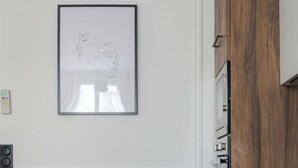 Una cucina moderna con mobili in legno, un quadro appeso al muro e un'area pranzo con due sedie.