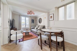 Un salon comprenant un canapé, des fauteuils, une table, un téléviseur et un ventilateur de plafond.