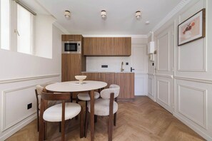 Une cuisine moderne avec des meubles en bois, une table de salle à manger ronde et un plan de travail blanc.