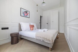 Ein Schlafzimmer mit einem Bett, einem Nachttisch, einer Wandleuchte und einer Tür.