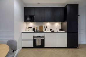 Eine moderne Küche mit dunklen Schränken, einem eingebauten Backofen und einer Kaffeemaschine.