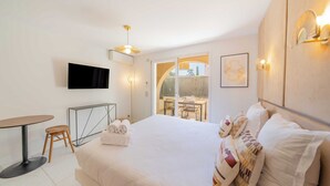 Hotellihuone, jossa on sänky, televisio, ruokailutila ja parveke.