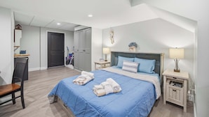 Quarto com uma cama, duas mesas de cabeceira, uma cadeira, escrivaninha e guarda-roupa.