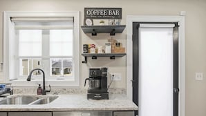 Cozinha com bancada de café, cafeteira Keurig e pia.