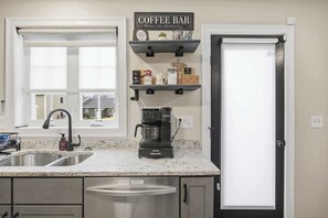 Una cocina con barra de café, una cafetera Keurig y un lavamanos.
