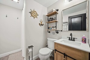 Une salle de bain équipée de toilettes, d’un lavabo et d’étagères où sont rangés les articles de toilette.