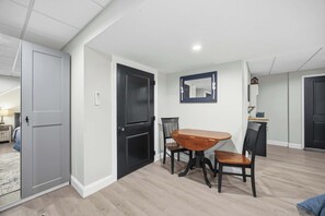 Un coin repas avec une table et des chaises en bois, une porte noire et un miroir au mur.