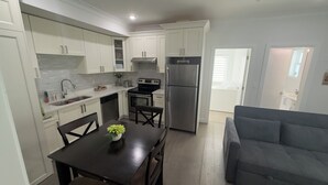 A modern kitchen with white cabinets, a stainless steel refrigerator, and a dining table with chairs. - Cozy and new self contained apartment in our home in Mission, British Columbia (Mission)
