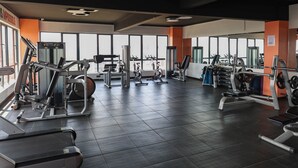 Ein Fitnessstudio mit verschiedenen Trainingsgeräten, großen Fenstern und modernem Design.